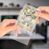 A hand inserting a toploader card into a clear resealable team bag, demonstrating ease of use.
