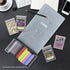 Open graded card holder with colorful slabs on black desk, surrounded by trading cards, notebook, coffee, and phone