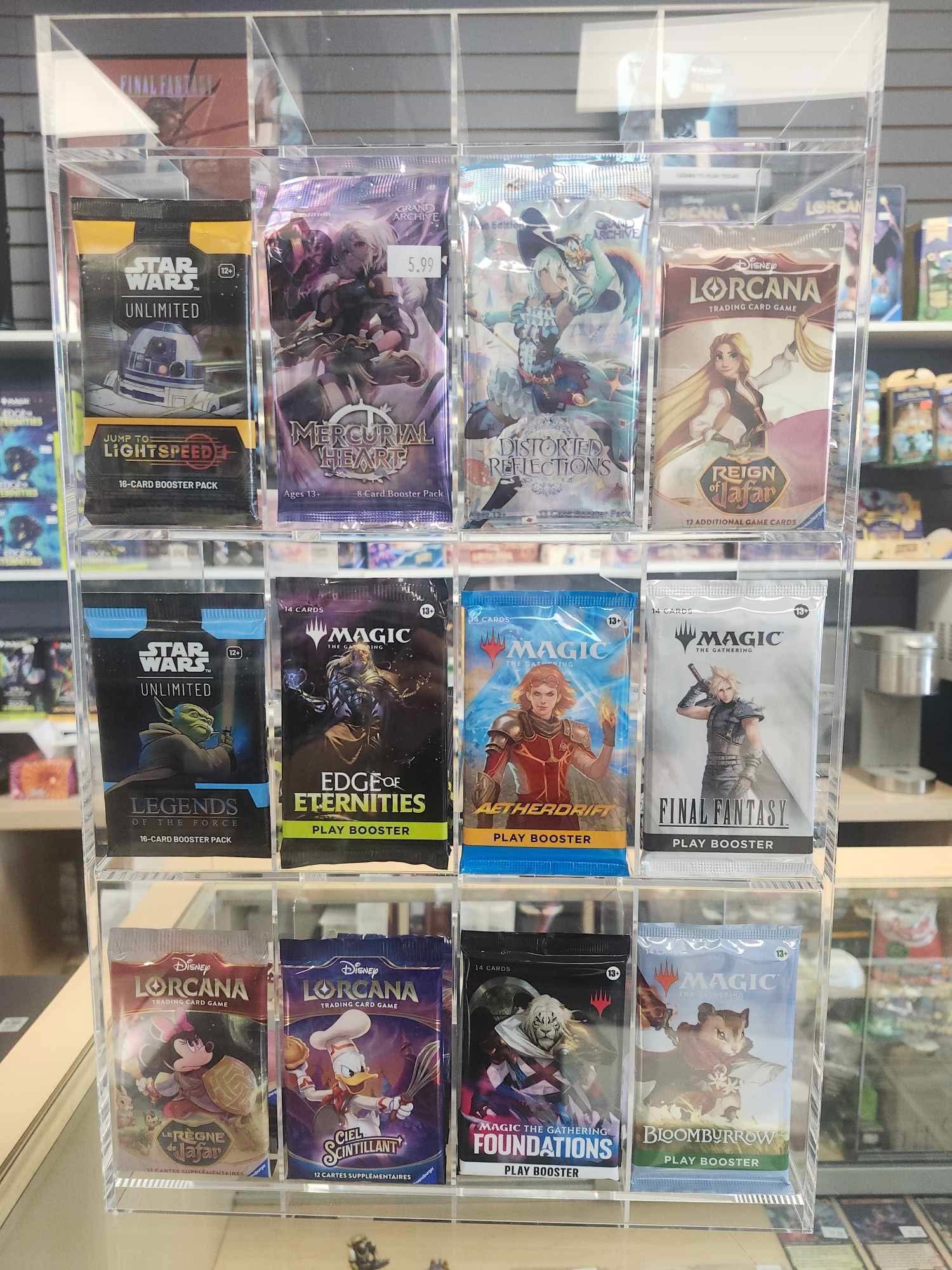 Front view of a clear acrylic display stand holding assorted booster packs, including Lorcana, Star Wars, and Magic: The Gathering, on a plain background.