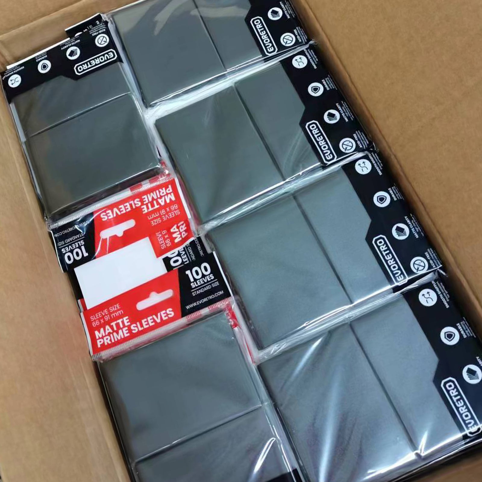 Multiple packs of EVORETRO Matte Card Sleeves in Black, standard size 66 x 91 mm, laid flat inside a box. Packaging features a black and red design with product details clearly visible.