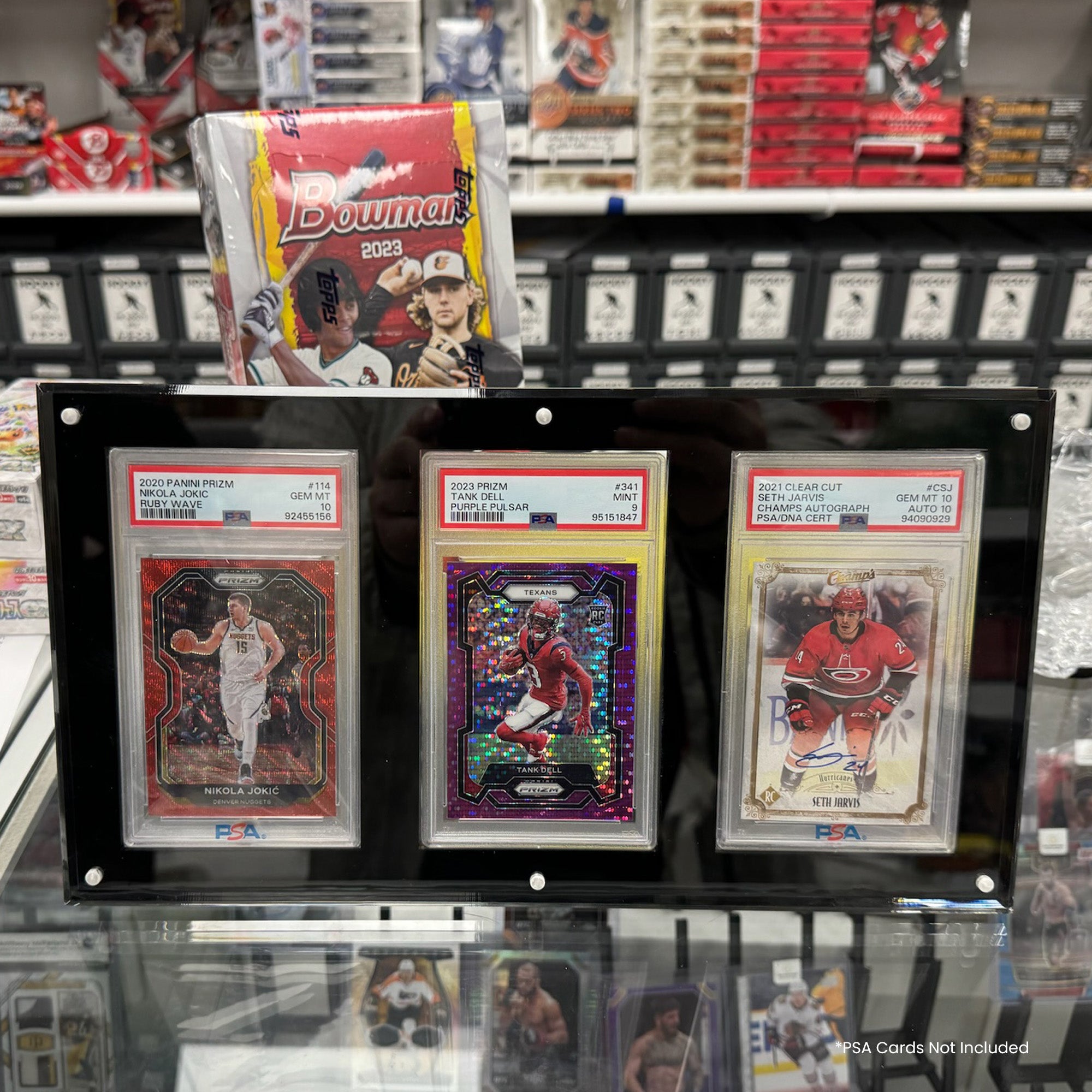 Collection of sports trading cards in a display case with various card packs in the background.