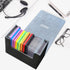 Open graded card holder with colorful slabs on a white desk setup beside laptop, headset, glasses, and notepad